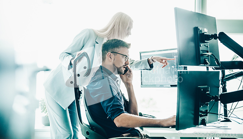 Image of Stock broker business team trading online watching charts and data analyses on multiple computer screens in modern corporate work station office.