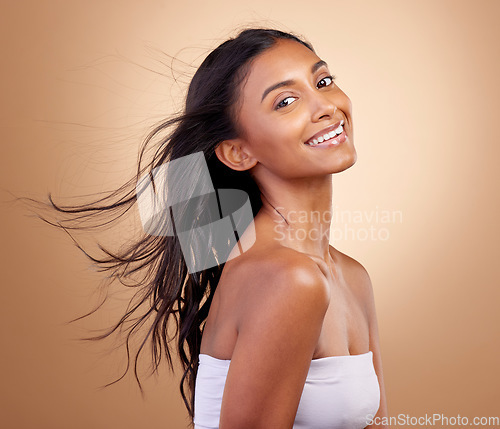 Image of Salon, hairstyle and beauty with indian woman or shine in brown studio background. Haircare, shine and happy face with wind or growth for glow with keratin treatment in mockup or natural cosmetics.