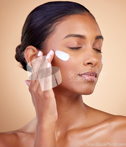 Image of Face, cream and woman with eyes closed for skincare cosmetics, dermatology or aesthetic makeup on studio background. Indian female model, lotion and facial sunscreen for clean beauty, glow and shine