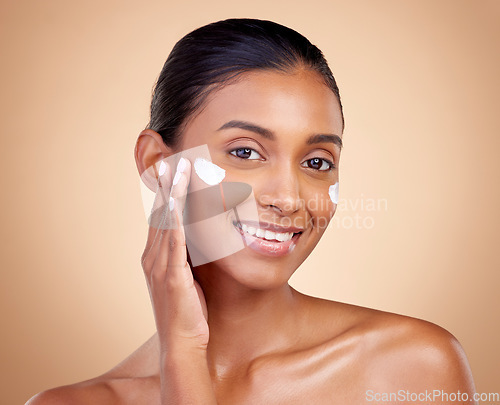 Image of Face, cream and portrait of indian woman, skincare cosmetics and aesthetic dermatology on studio background. Happy young female model, lotion and facial sunscreen for clean beauty, glow and self care