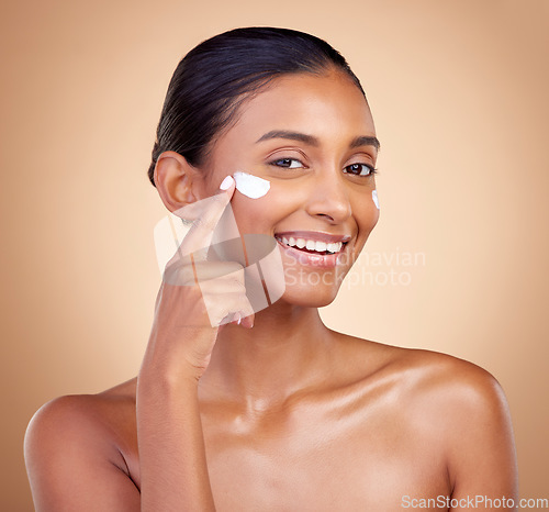 Image of Face, cream and portrait of happy indian woman, makeup cosmetics and skincare dermatology on studio background. Young female model, lotion and facial sunscreen for clean beauty, shine and self care