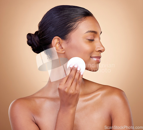 Image of Woman, cotton pad and skincare of face cosmetics for aesthetic wellness on studio background. Happy indian female model, clean beauty and facial dermatology product for makeup removal, shine and glow