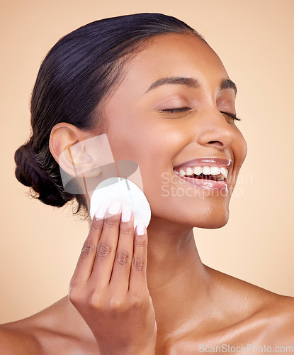 Image of Happy woman, cotton pad and skincare of face cosmetics, aesthetic wellness and studio background. Indian female model, clean beauty and facial cleaning product for makeup removal, dermatology or glow