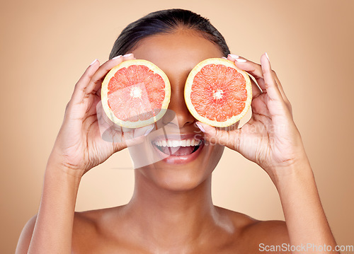 Image of Grapefruit, beauty and eyes of happy woman in studio, vitamin c nutrition or natural glow. Face of female model, healthy skincare or smile with citrus fruits, eco dermatology or sustainable cosmetics