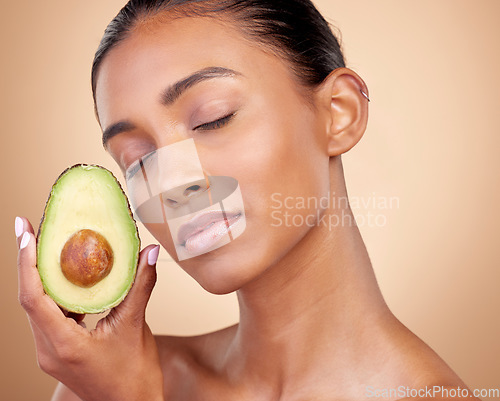 Image of Avocado, beauty and woman in studio, background and eyes closed for aesthetic glow. Face of indian model, natural skincare and fruit for sustainable cosmetics, vegan dermatology and facial benefits