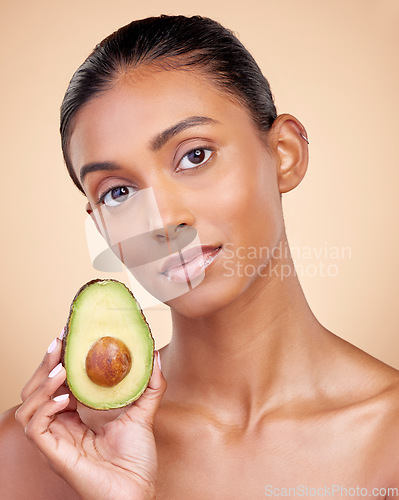 Image of Avocado, skincare and woman in portrait for healthy face and natural beauty on studio brown background. Young indian person or model with green fruits, vitamin c benefits and dermatology or cosmetics