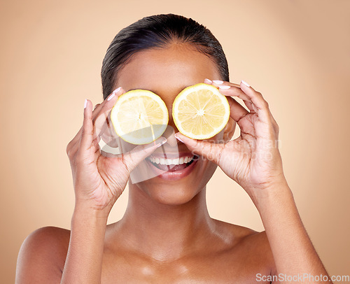 Image of Face, skincare or happy woman with lemon for health, wellness or vitality isolated on studio background. Girl, smile or female model with natural citrus fruit for vitamin c, minerals or nutrition