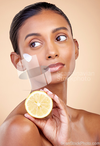 Image of Woman, lemon and cream for skincare, natural beauty product and cosmetics or vitamin c benefits while thinking. Face sunscreen, fruits and young person for skin dermatology on studio brown background