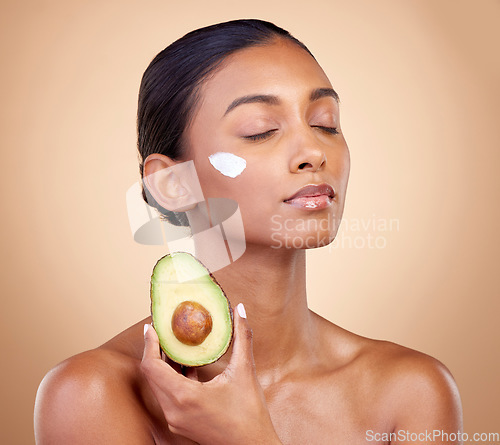 Image of Beauty, cream and skincare with woman and avocado in studio for product, fruit and natural cosmetics. Spa, facial and lotion with face of model on brown background for vitamin c and self care