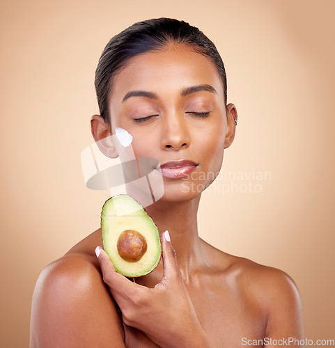 Image of Avocado, cream and skincare with face of woman in studio for product, beauty and natural cosmetics. Spa, facial and lotion with female model on brown background for vitamin c, fruit and self care