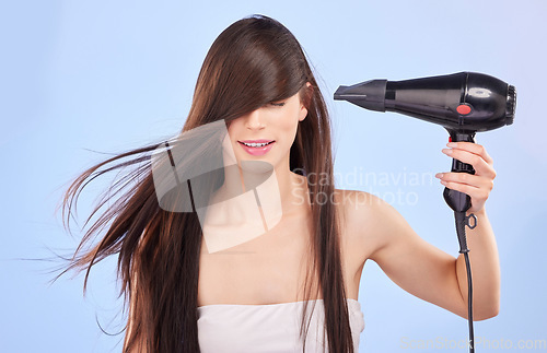 Image of Hair, dryer and woman in studio for beauty, cosmetics and shine on blue background. Female model, heating tools and electrical appliance for wind, clean haircare and smooth aesthetic texture in salon