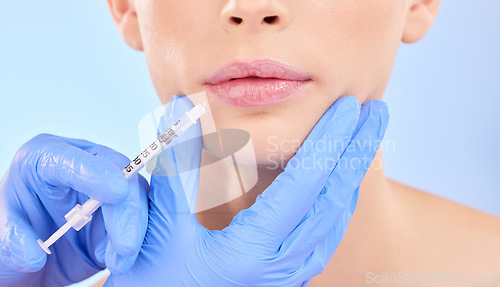 Image of Injection, woman and lips with plastic surgeon for beauty with botox or hands in studio with blue background. Face, syringe and doctor for injecting mouth with collagen or filler and implants.