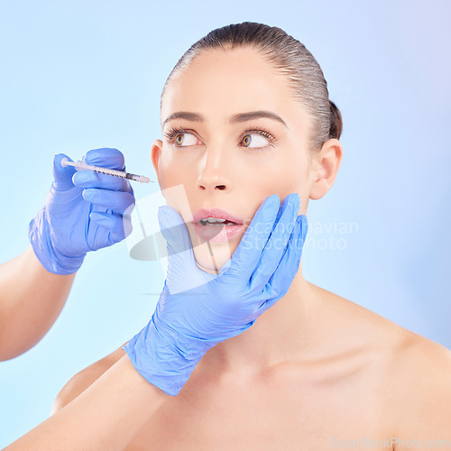 Image of Face, beauty and woman with plastic surgeon or injection for transformation in studio with blue background. Girl, filler and skincare for cosmetic with collagen or fear for doctor hands with syringe.