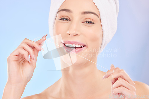 Image of Flossing, teeth and woman in portrait, dental and health with oral care isolated on blue background. Female model, morning routine and orthodontics, hygiene and cleaning mouth with thread in studio