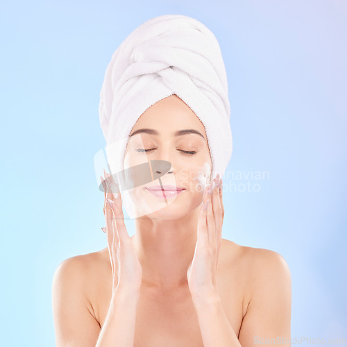 Image of Face, skincare and woman with soap, towel and isolated in studio on a blue background. Eyes closed, cosmetic and model washing, cleaning or hygiene with facial foam for health, dermatology or beauty