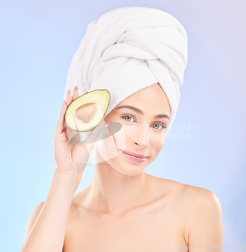 Image of Skincare, beauty and portrait of woman with avocado, makeup and facial detox with smile on blue background. Health, wellness and sustainability, model withface cleaning and towel on head in studio.