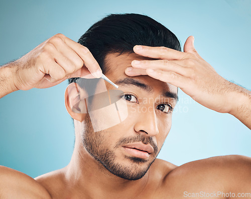 Image of Man, face and eyebrow tweezers, beauty and skin, hair removal and cosmetics on blue background. Grooming, hygiene and male model, portrait and wellness with treatment, tools and self care in studio