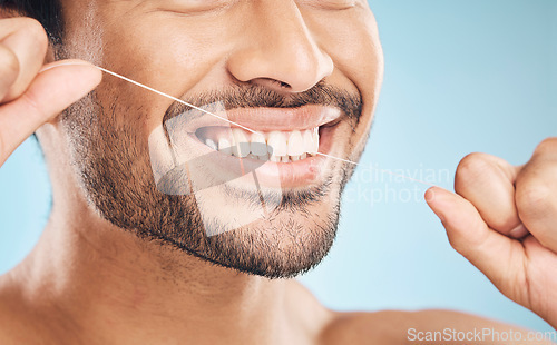 Image of Wellness, teeth closeup and flossing of a man with cleaning and dental health in a studio. Face, blue background and healthy male person with dental floss for mouth hygiene and healthcare with smile