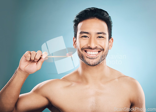 Image of Dental, portrait and Asian man with a toothbrush, oral hygiene and wellness against a blue studio background. Face, male person and happy model teeth cleaning product, toothpaste and fresh breath