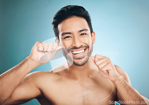 Image of Wellness, teeth and dental floss of a man portrait with cleaning and dental health in a studio. Face, blue background and healthy male person with flossing for mouth hygiene and healthcare with smile