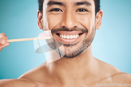 Image of Dental, portrait and Asian man with a toothbrush, fresh breath and wellness against a blue studio background. Face, male person and happy model teeth whitening, mouth cleaning product and toothpaste