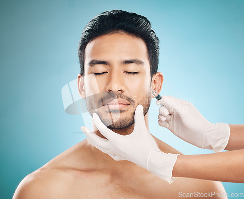 Image of Face, hands and transformation with a plastic surgery man in studio on a blue background for beauty enhancement. Aesthetic, botox or prp with a young male patient eyes closed in a clinic for skincare