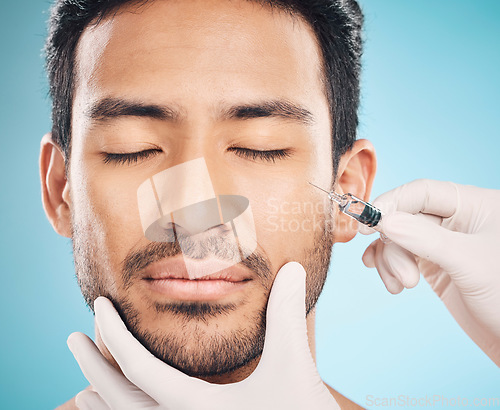 Image of Face, hands and change with a plastic surgery man in studio on a blue background for beauty enhancement. Aesthetic, botox or prp with a young male patient eyes closed in a clinic for skincare closeup