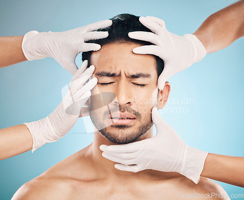 Image of Face, hands and plastic surgery with a nervous man in studio on a blue background for beauty enhancement. Aesthetic, botox and change with a young male patient eyes closed in a clinic for skincare