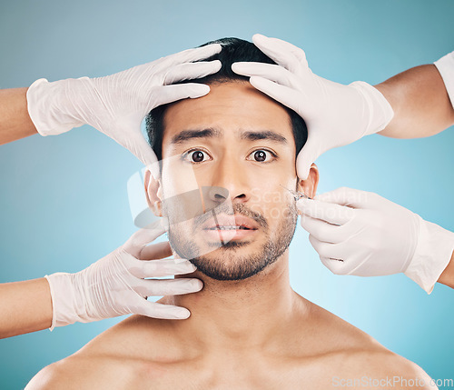 Image of Portrait, hands and plastic surgery with a nervous man in studio on a blue background for beauty enhancement. Face, botox and change with a young male patient looking worried in a clinic for skincare