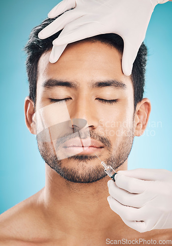 Image of Face, hands and botox with a plastic surgery man in studio on a blue background for beauty enhancement. Aesthetic, transformation or change with a young patient eyes closed in a clinic for skincare