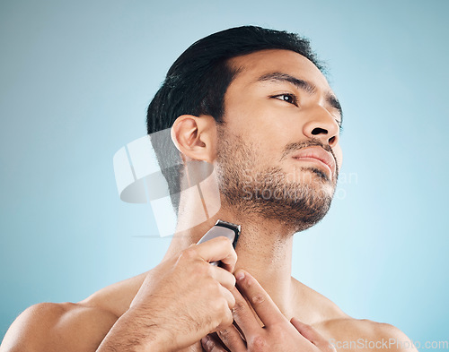 Image of Face, shaving and electric razor with a man in studio on a blue background for personal hygiene, skincare or grooming. Beauty, wellness or cosmetics with a young male in the bathroom for hair removal