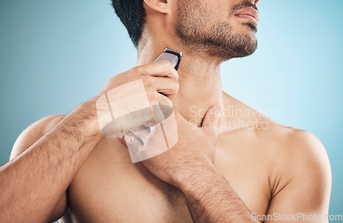 Image of Hands, shaving and electric razor with a man in studio on a blue background for personal hygiene or grooming. Beauty, wellness and cosmetics with a young male in the bathroom for hair removal