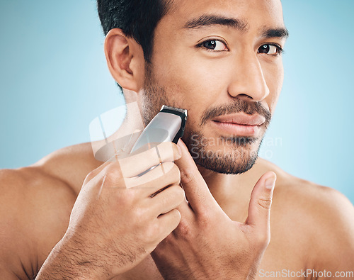 Image of Portrait,, electric shaving and grooming with a man in studio on a blue background for personal hygiene or skincare. Face, wellness and cosmetics with a young male in the bathroom for hair removal