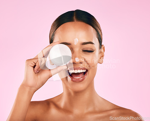 Image of Happy woman, cream in container and beauty, skincare and moisturizer dot on face on pink background. Natural cosmetics, self care and lotion, sunscreen and dermatology with female model in studio