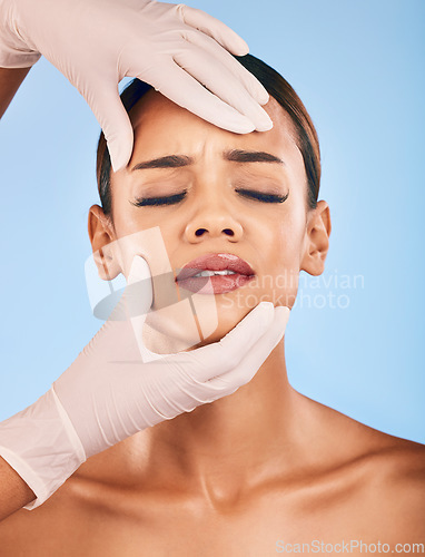 Image of Plastic surgery, hands and woman in pain for skincare in studio isolated on a blue background. Beauty, dermatology or model with doctor for cosmetic transformation, aesthetic change or face treatment