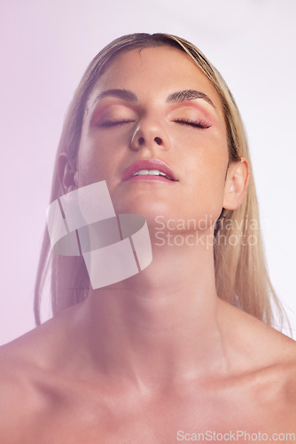 Image of Face, beauty and skincare with a model woman in studio on a gray background in ambient lighting for feminine desire. Luxury, makeup or cosmetics with a young person posing eyes closed for wellness