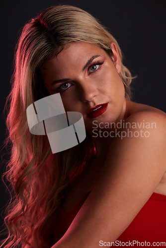 Image of Portrait, luxury and makeup with a model woman in studio on a dark background in red lighting for desire. Face, beauty or skincare with a young female person posing for natural feminine confidence