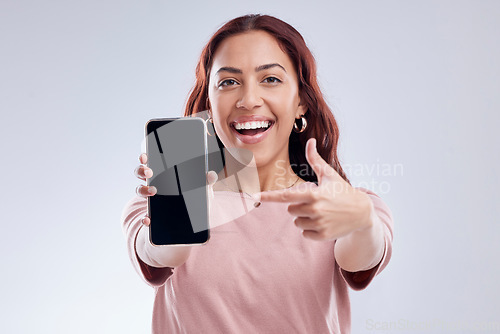 Image of Happy woman is pointing at phone screen, mockup and marketing, mobile app ads on white background. Website promo, advertising and female ambassador in portrait with social media branding in studio