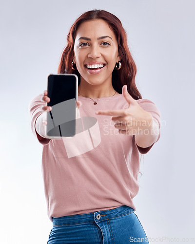 Image of Woman is pointing at phone screen, mockup and advertising, mobile app ads on white background. Website promo, marketing and female brand ambassador in portrait with social media branding in studio