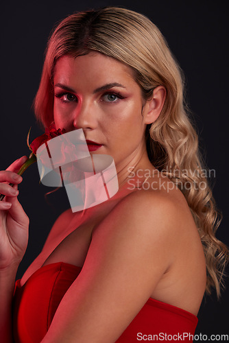 Image of Portrait, beauty and rose with a model woman in studio on a dark background for valentines day. Face, skincare or flower with a young female person posing in red for natural feminine confidence