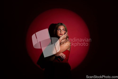 Image of Fashion, spotlight and red with a model woman in studio on a dark background for classy elegance or style. Beauty, aesthetic and luxury with a confident young female person standing in a dress