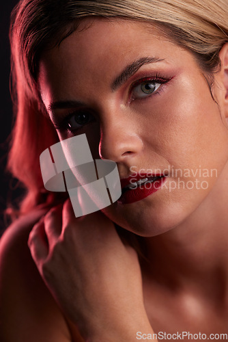 Image of Portrait, beauty and makeup with a model woman in studio on a dark background in red lighting for desire. Face, skincare or cosmetics with a young female person posing for natural feminine confidence
