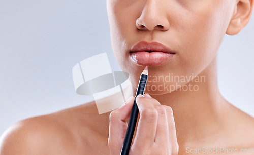 Image of Makeup, mouth and woman with lip pencil in studio for beauty, cosmetics and color on grey background. Liner, filling and hand of female model with beauty product for glamour, routine or application