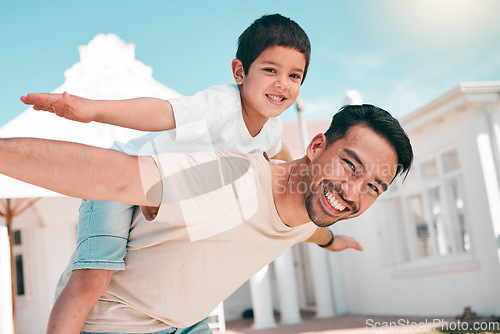 Image of Happy, airplane and portrait of a father with his child in the outdoor garden at their family home. Playful, smile and young dad carrying his boy kid on his back while bonding and playing together.