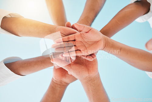 Image of Circle, low angle and team with hands together for collaboration, unity or support by a blue sky. Teamwork, diversity and group of people in an outdoor huddle for motivation, solidarity or community.