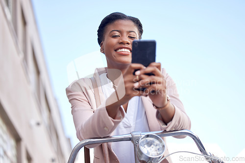 Image of Business woman in city with bicycle, phone and smile on commute, checking location or social media. Eco friendly transport bike, cycling and happy African girl typing with mobile app on work travel.