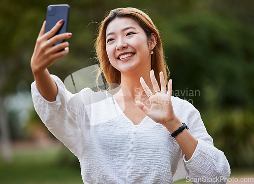 Image of Happy, woman and wave hello to phone for video call, blog or social media, communication or post on internet in the park. Selfie, face and girl with a smile for smartphone conversation or film