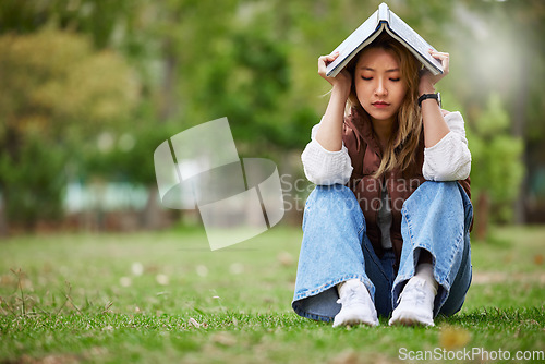 Image of Study, sad and book with woman in park for studying, thinking or depression mockup. College, mental health and education with asian student on grass in nature for burnout, anxiety and fatigue problem