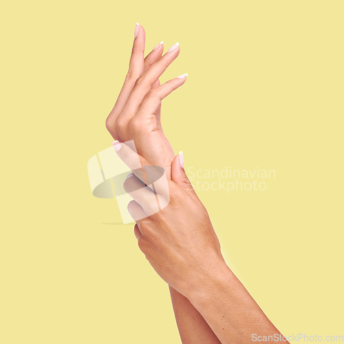 Image of Skincare, yellow background and hands of woman in studio for wellness, cosmetics and manicure treatment. Spa aesthetic, beauty salon and isolated palms of girl apply lotion, nail cream or moisturizer