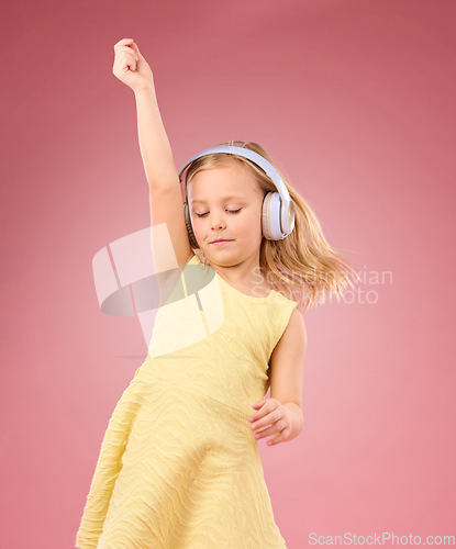 Image of Music headphones, dance and girl kids in studio, pink background or color backdrop for happiness. Happy children, dancing and listening to radio, audio and sound with energy, fun songs and freedom